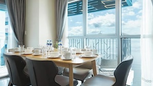 Un coin repas avec une table dressée pour quatre personnes, de grandes fenêtres offrant une belle vue et une balustrade de balcon.