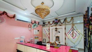 A reception area with a pink counter, a chandelier, and festive decorations. - Dhanas Residency Auroville (Kuilapalayam)