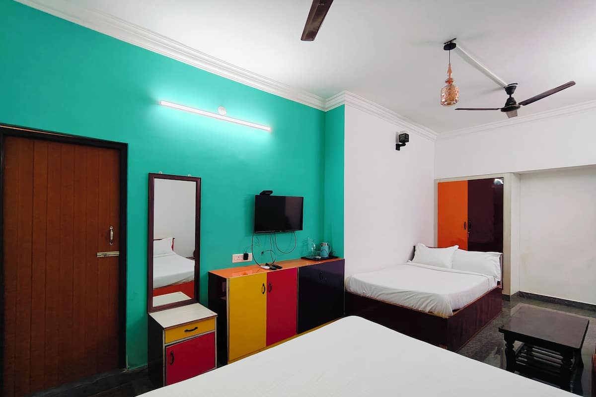 A hotel room with a large bed, a TV, a wardrobe, and a ceiling fan.