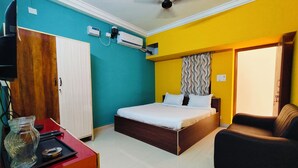 A bedroom with a bed, a chair, a desk, and an air conditioning unit. - Dhanas Residency Auroville (Kuilapalayam)