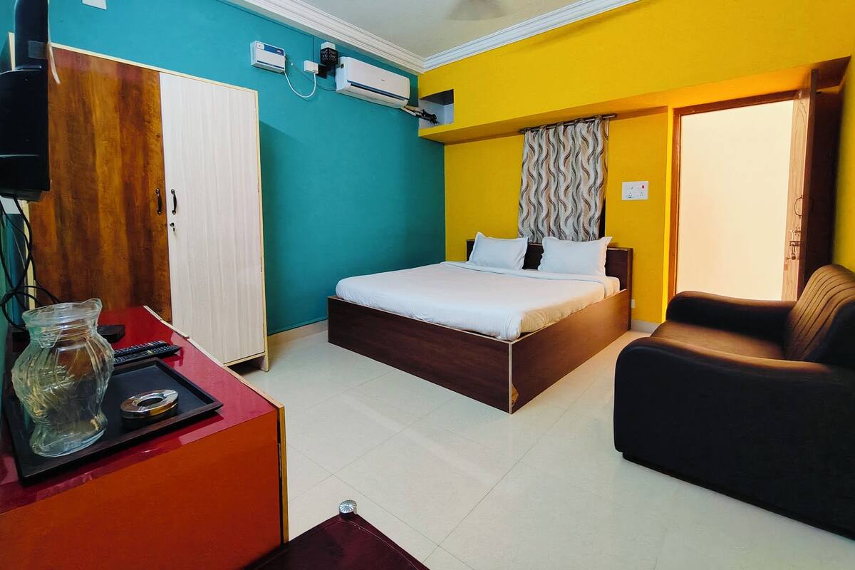 A bedroom with a bed, a chair, a desk, and an air conditioning unit.