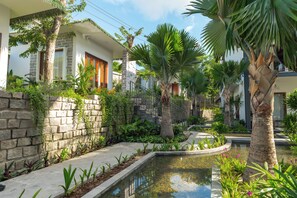 A residential property with a stone wall, a small garden with various plants, a paved pathway, and a central water feature. - Pandora Sand Hill Mui Ne Resort (Mui Ne)