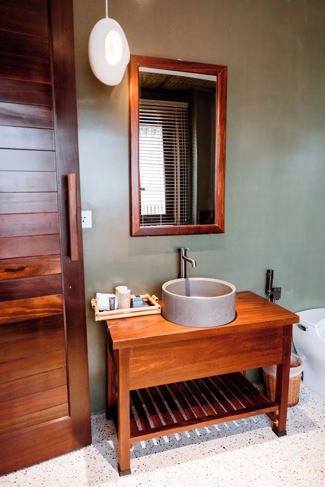 Une salle de bain avec un meuble-lavabo en bois, un lavabo rond et un miroir au-dessus.