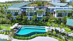 A modern resort with a large swimming pool, lush greenery, and solar panels on the roofs. - Pandora Sand Hill Mui Ne Resort (Mui Ne)