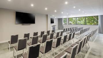 A conference room with rows of chairs, a large flat-screen TV, and a podium.