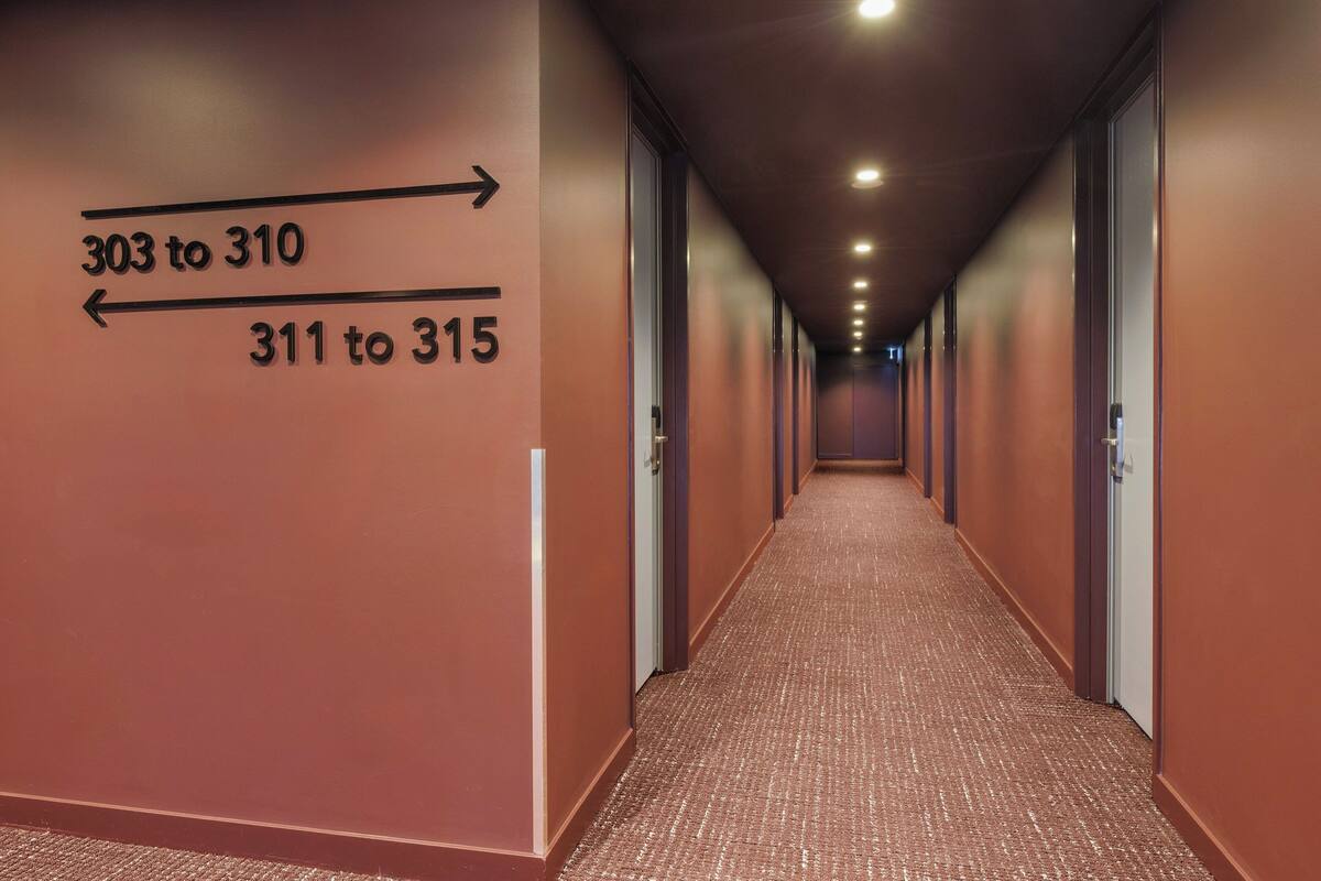 A hotel corridor with directional signs indicating room numbers 303 to 310 and 311 to 315.