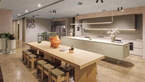 Una cocina moderna con una isla grande, zona de estar y un cartel visible que dice 'BOND'.