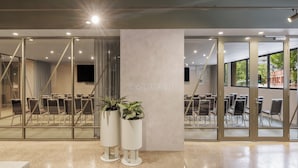 Una sala de conferencias moderna con paredes de vidrio, sillas blancas y dos plantas en macetas.
