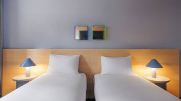 A double bed with a wooden headboard, two bedside lamps, and two wall-mounted mirrors.