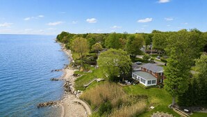 A coastal property with a large house, a private beach, and a view of the sea. - Lake Erie Beachfront Retreat - 8 BR + Private Beach & Hot tub! (Madison)