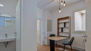 Et moderne badeværelse med vask, spejl og et træbord med en stol.