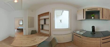 Un espace de vie compact comprenant une cuisine, un coin repas et une petite chambre.