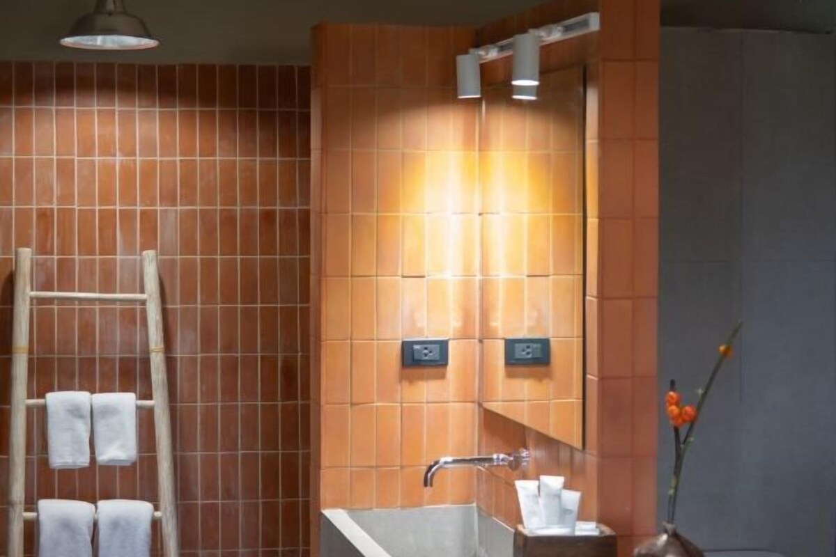 A bathroom with a wooden ladder, a sink, and a mirror with lights.