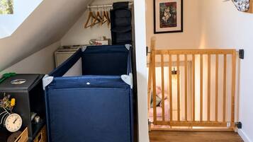 Une pièce avec un lit en mezzanine, un berceau, un plancher en bois, un radiateur fixé au mur et une fenêtre avec vue.