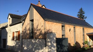 Una casa de dos pisos con techo inclinado, revestimiento de madera y una chimenea.
