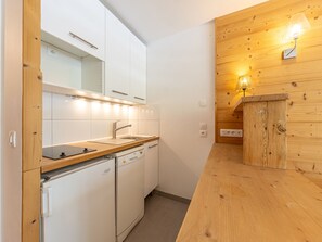 Uma cozinha compacta com armários brancos, pia de aço inoxidável e lava-louças embutida.