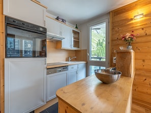 A modern kitchen with white cabinetry, a stainless steel sink, and a wooden countertop.