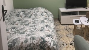 A room with a bed, a TV, a small table, and a chair. - T2 in charming Ardèchois village (SAINT-JULIEN-EN-SAINT-ALBAN)