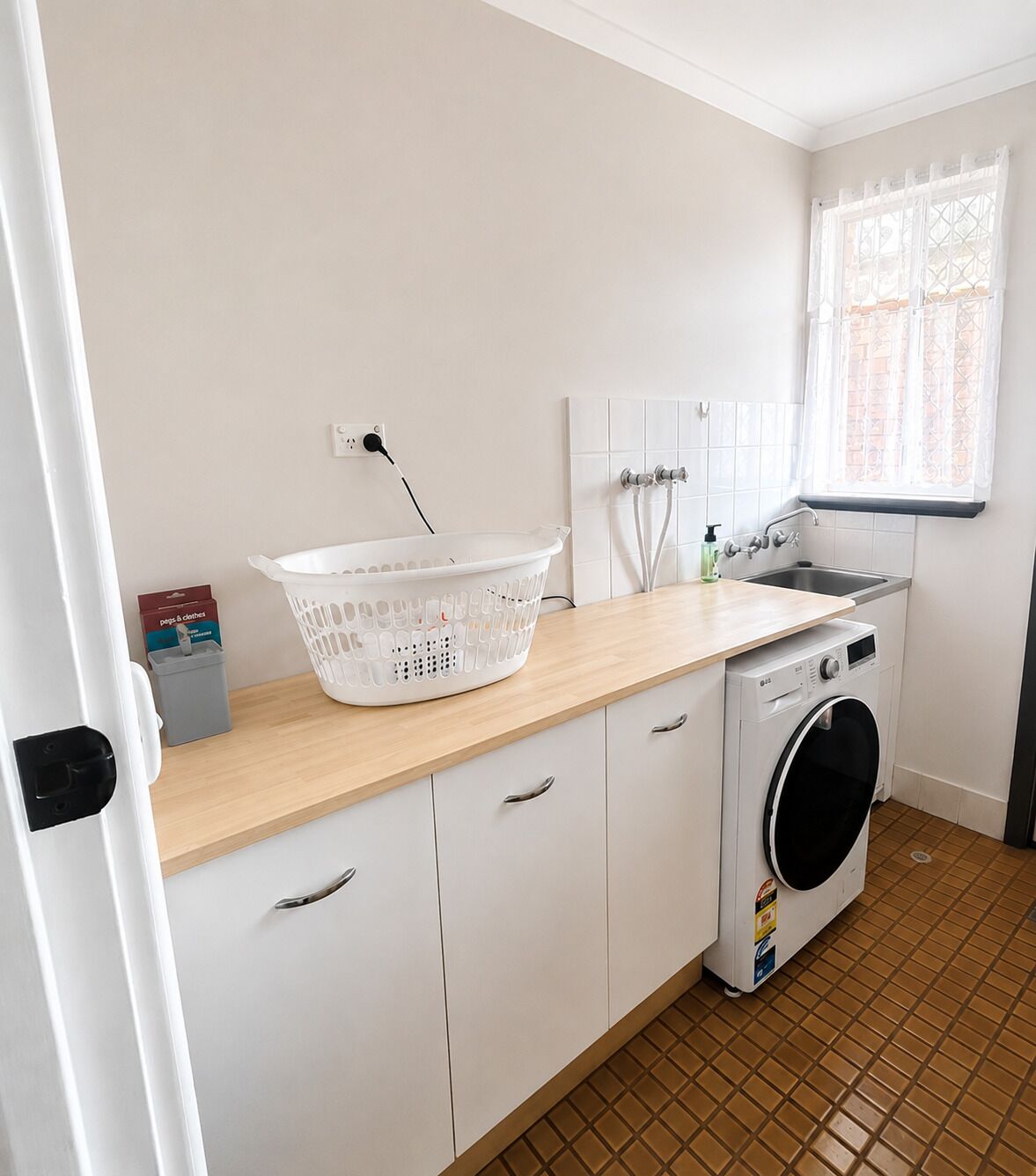 A laundry area with a washing machine, a drying rack, and a sink.