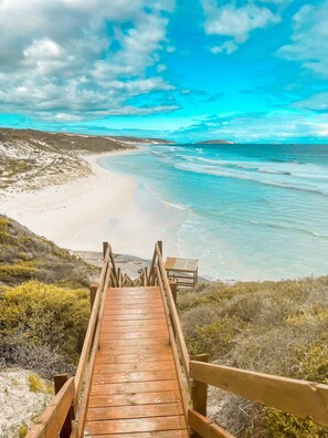 A wooden boardwalk leading to a beach with clear turquoise waters and a sandy shore. - Smugglers Cove (Castletown)