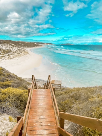 A wooden boardwalk leading to a beach with clear turquoise waters and a sandy shore.. Smugglers Cove