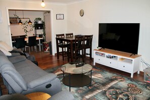 A living room with a sofa, TV, and a dining area with chairs and a table. - Smugglers Cove (Castletown)