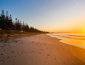 A beach with footprints, trees, and a clear sky. - Smugglers Cove (Castletown)