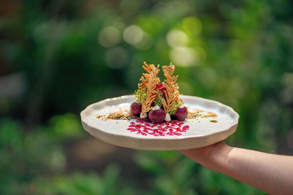 A hand holding a plate with a food dish. - Hotel Bent (Oisterwijk)