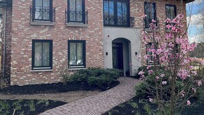 A two-story house with a brick facade, multiple windows, and a curved brick pathway leading to the entrance. - Hotel Bent (Oisterwijk)