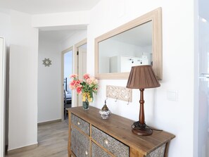 A hallway with a wooden console table, a mirror, and a lamp.