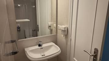 A bathroom with a pedestal sink, a mirror with lights, a door, and a hand dryer.