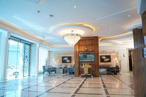 A spacious lobby with a large chandelier, a reception desk, and a seating area with sofas and a coffee table. - Palette Luxury Credi Hotel (Riyadh)