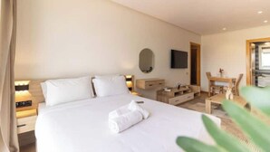 A hotel room with a bed, bedside table, lamp, and a small desk with a chair.