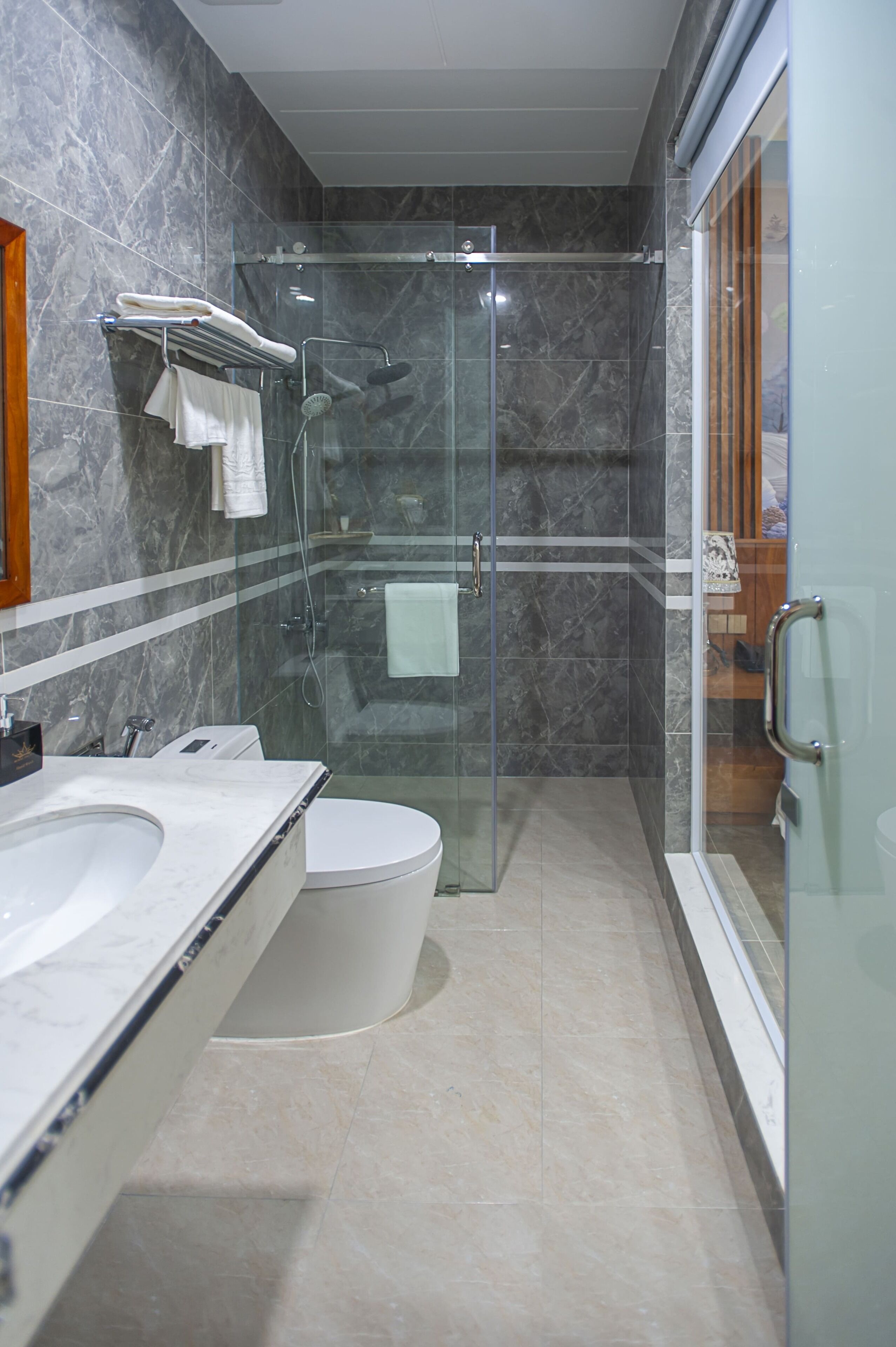 A modern bathroom with a glass-enclosed shower, a white toilet, and a double sink with a marble countertop.
