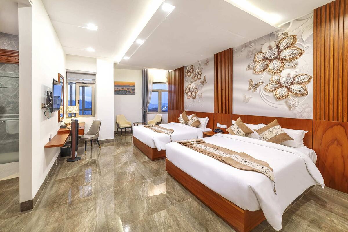 A hotel room with two beds, a desk, and a view of the city.