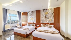 Une chambre d’hôtel avec deux lits, une vue sur la ville et un grand décor mural représentant des motifs floraux.