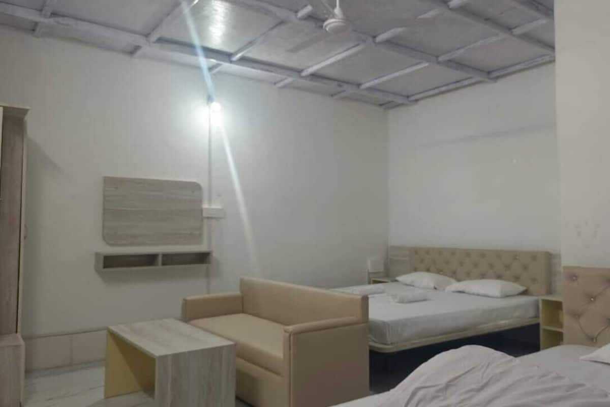 A bedroom with a bed, a sofa, and a bedside table.