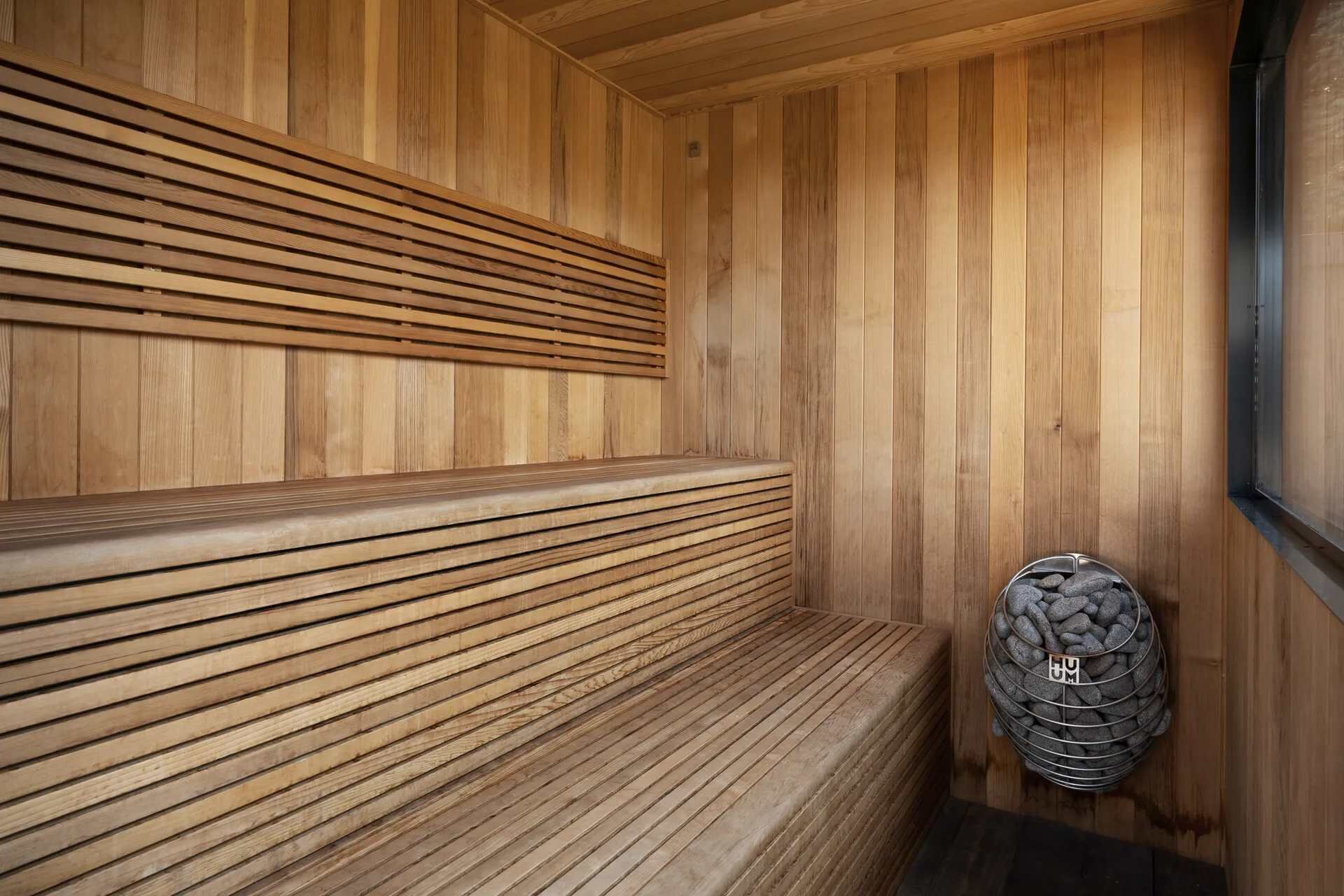 Uma sauna de madeira com bancos e um recipiente cheio de pedras.