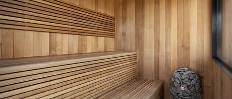 Uma sauna de madeira com bancos e um recipiente cheio de pedras.
