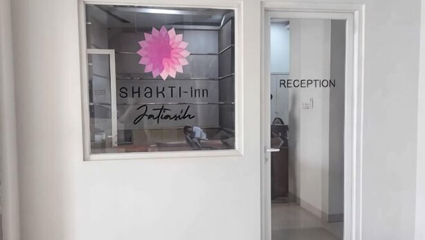 Un espace d’accueil avec une enseigne indiquant « SHAKTI-inn » et une grande décoration florale rose.