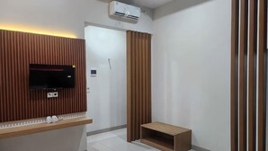 Une chambre d’hôtel moderne dotée d’un téléviseur à écran plat fixé sur un panneau en bois, d’un banc et d’une porte coulissante.