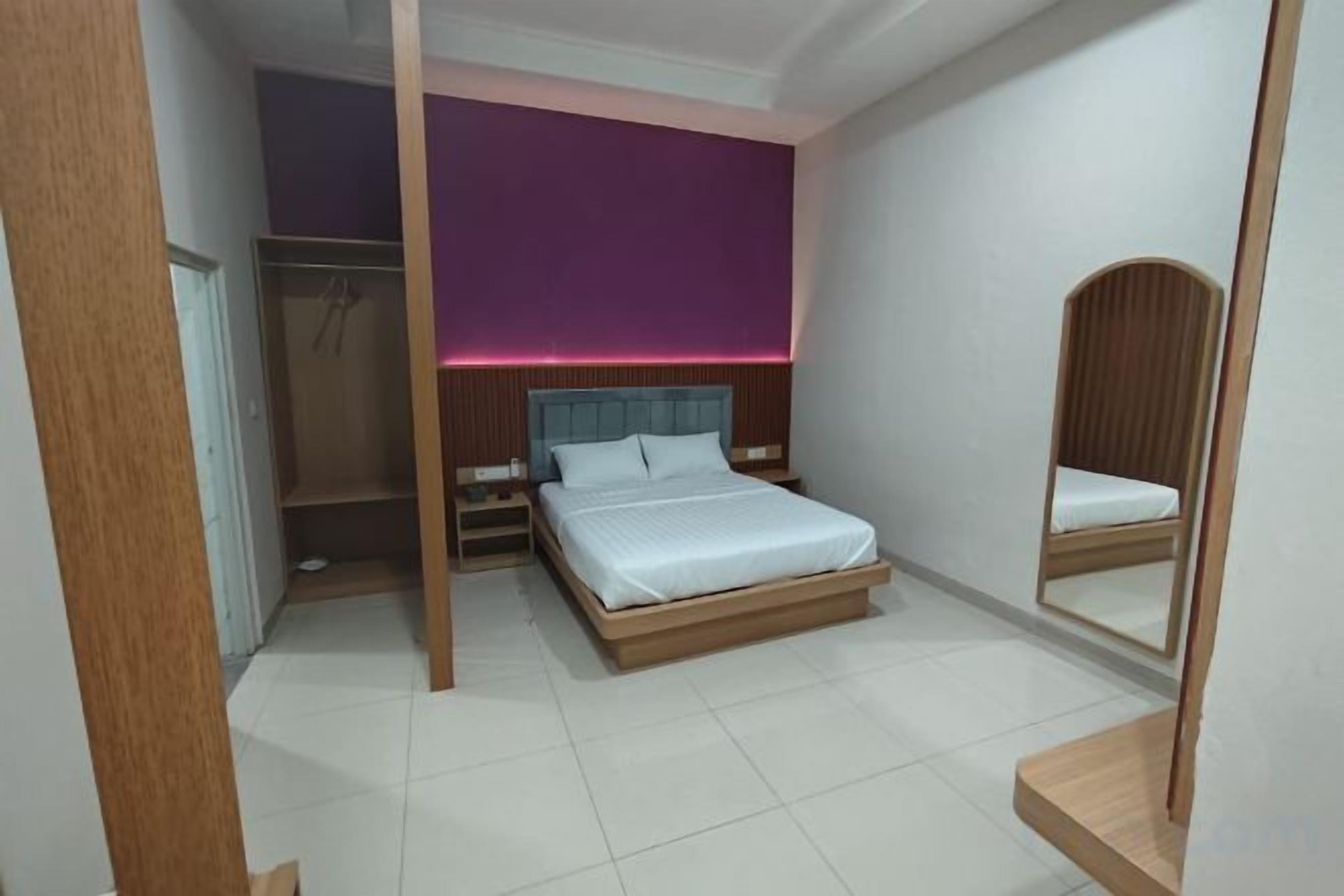 Une chambre à coucher comprenant un lit, des tables de chevet, une armoire et un miroir.
