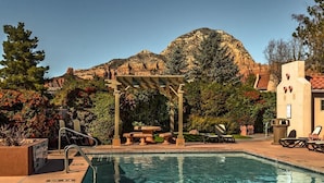 Un espace piscine agrémenté d’une pergola, de chaises longues et offrant une vue sur les montagnes.