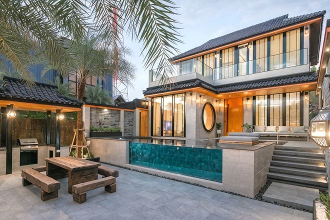A modern house with a swimming pool, outdoor seating, and a staircase leading to the entrance.
