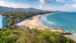 Vista costera con playa, océano y montañas al fondo.