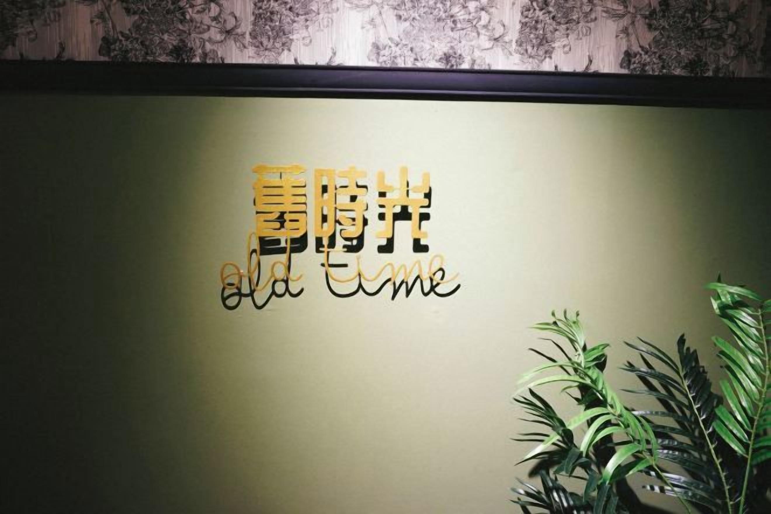 A wall with a sign that reads 'Old Time' in English and another script, possibly Chinese. There are plants to the right.