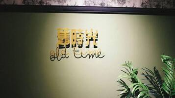 A wall with a sign that reads 'Old Time' in English and another script, possibly Chinese. There are plants to the right.