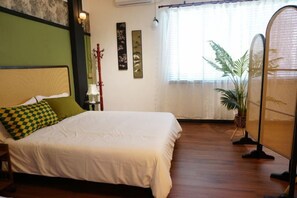 A neatly made bed with a checkered pillow, a bedside lamp, and a potted plant. - Old Time (Tawau)