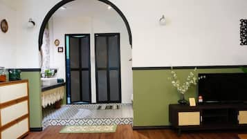 Una sala de estar con televisor, sofá, una mesita de centro y un jarrón decorativo.