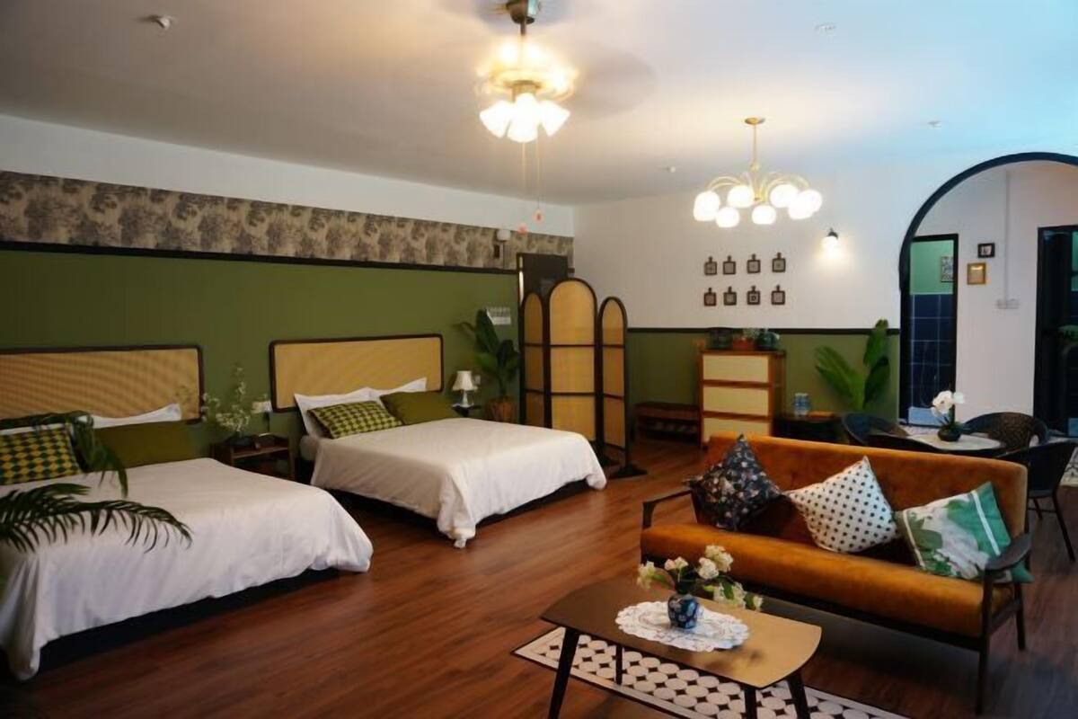 A hotel room with two beds, a sofa, a coffee table, and a decorative wall.